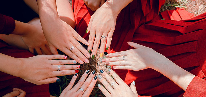Frauen halten ihre Hände mit bunt lackierten Findernägeln zusammen